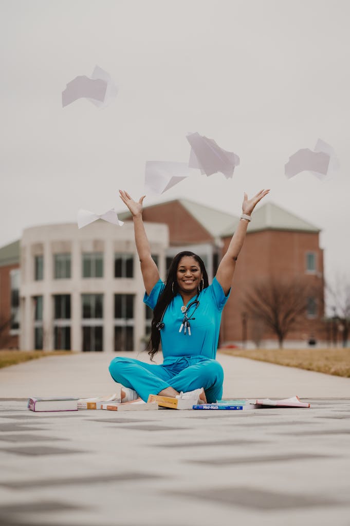 Happy medical student in blue scrubs celebrates graduation by tossing papers outdoors. How to sell a medical practice