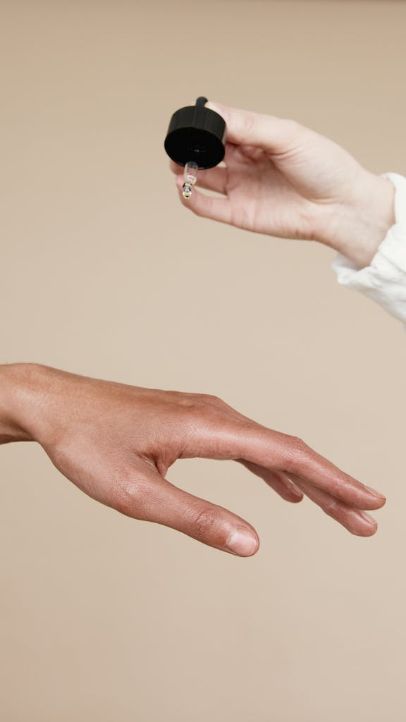 Photo by Artem Podrez - Dike Law Group Two hands applying skin care oil with a dropper. Ideal for wellness and beauty themes.